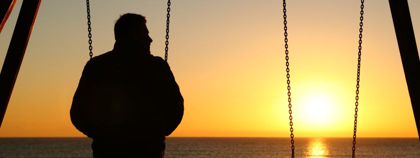 Man on swing looking at sunset