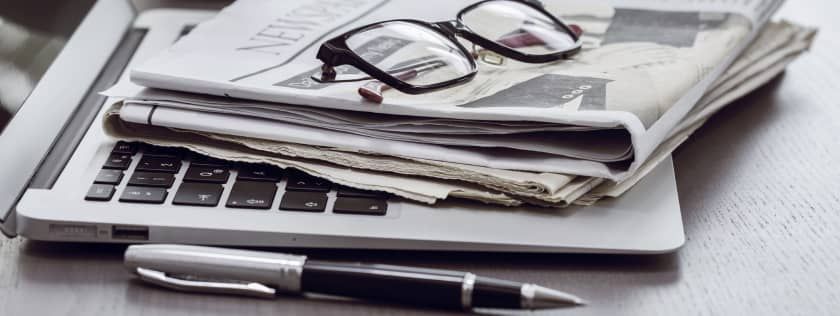 Newspapers sitting on top of laptop