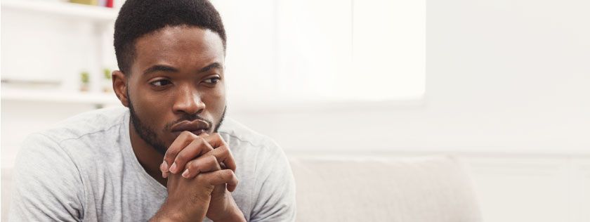 Man sitting on couch looking thoughtful
