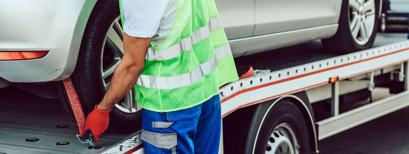 Man loading a car on to a car transporter truck