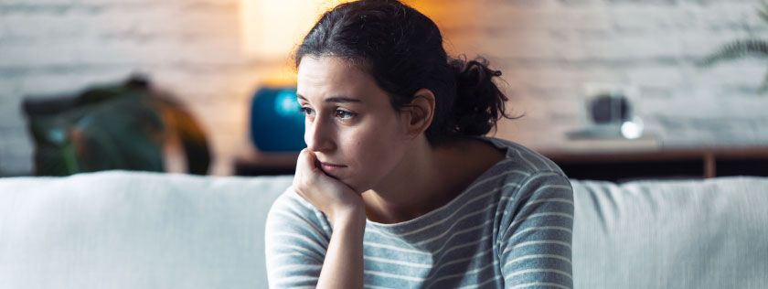 Woman sitting on sofa thinking