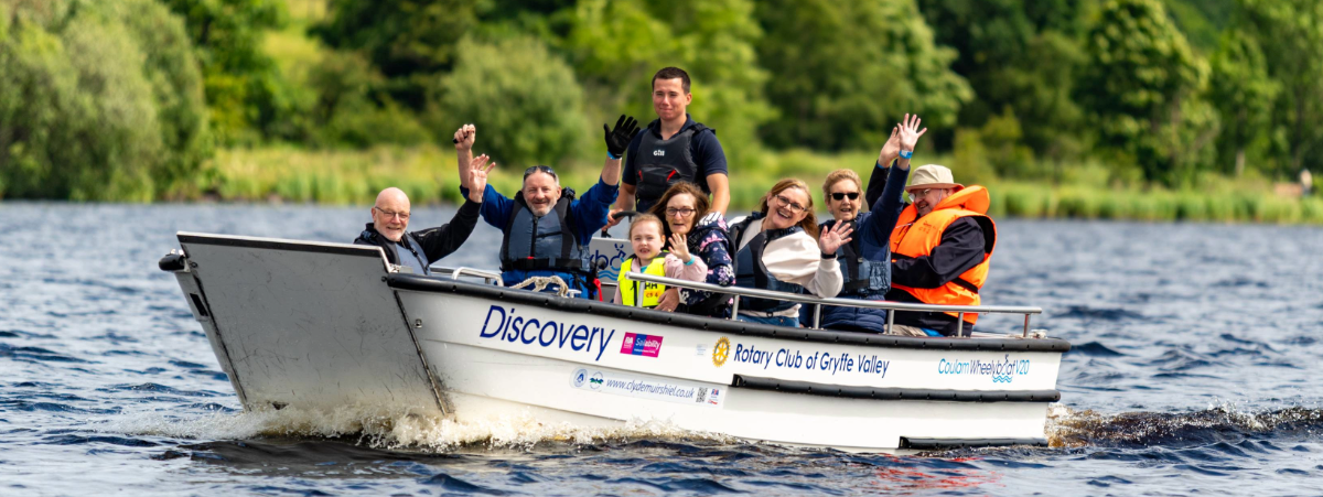 People in a boat on the water smiling and waving