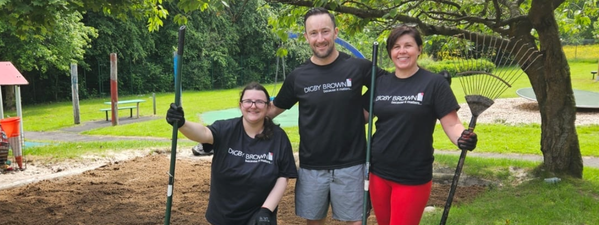 Three staff members from our Glasgow office standing in a garden with gardening tools