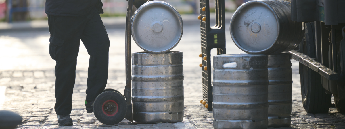 Delivery man bringing beer kegs out of a lorry on a trolley