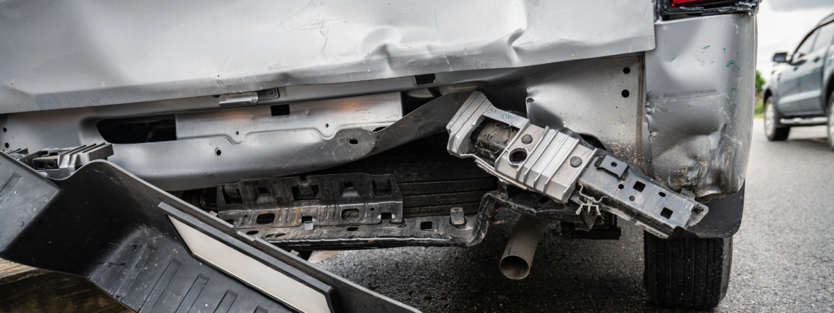 An image showing the back of a silver van which has been hit by a car. The back of the van is dented and the bumper has fallen off.
