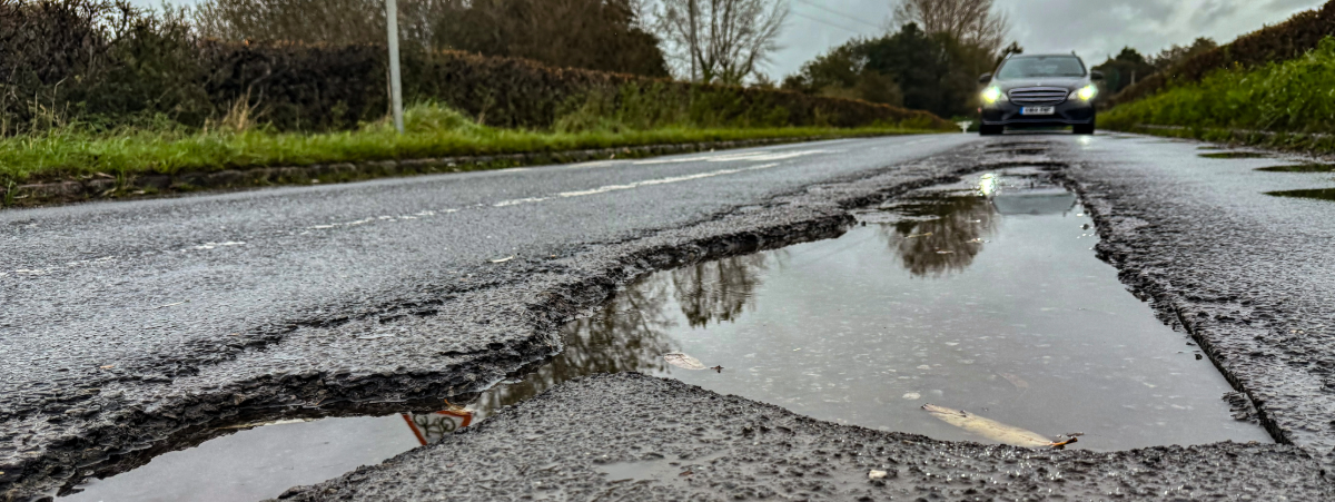 A large pothole on the road filled with water