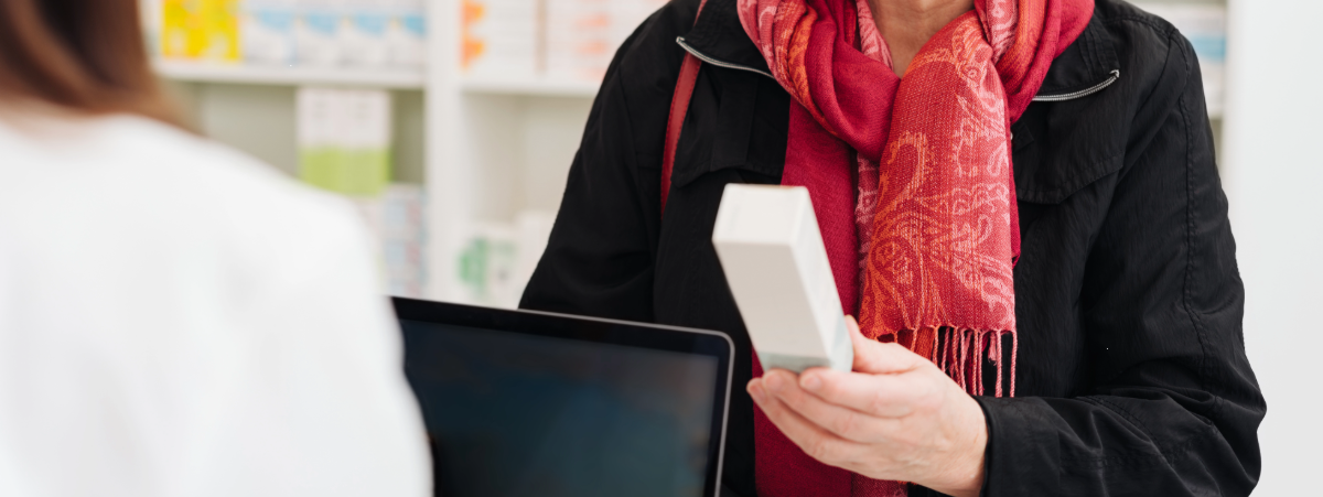 A woman is pictured holding medicine in a pharmacy