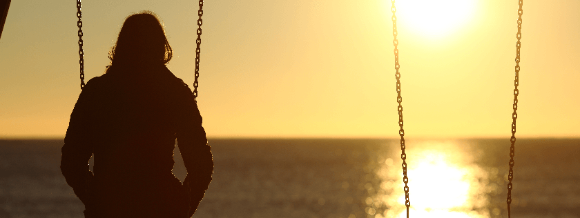 Woman sitting on swing watching sunset