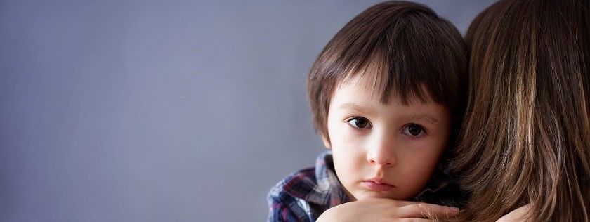 Unhappy child looking over mum's shoulder