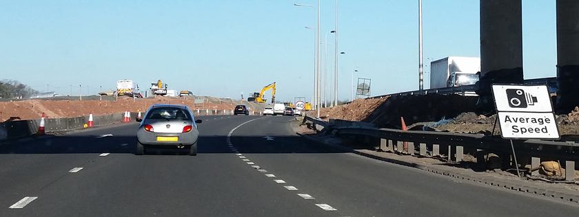 Car travelling along motorway with road works and average speed camera