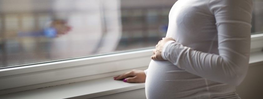 Pregnant woman standing at window
