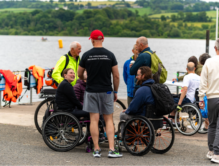 Chris Stewart, Partner in our Serious Injury team, standing with a group of wheelchair users. The back of his t-shirt reads 'I'm volunteering because it matters...'