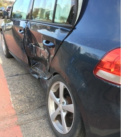 Image shows the side of David's car impacted by the collision. The rear passenger side door has concaved and the airbags have deployed within the vehicle.