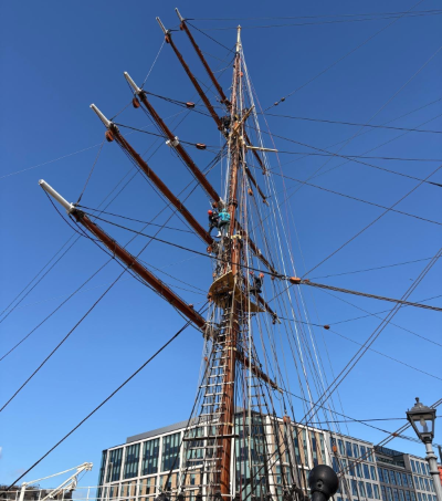 The image shows a Digby Brown employee harnessed to the Discovery mast ready to zipline to the waterfront