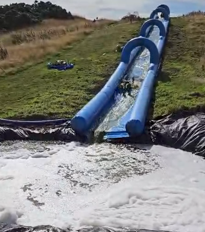 Image shows the inflatable slide at the Rainbow Run with someone from Digby Brown halfway down the slide