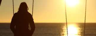 Woman sitting on swing watching sunset