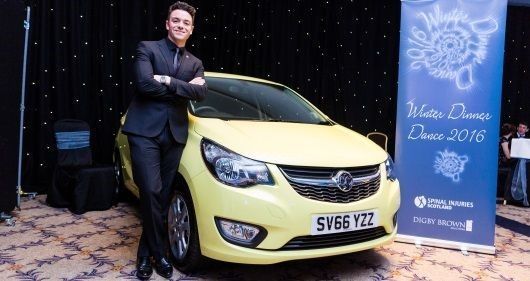Des Clarke from Global Radio standing next to the Grand Prize - a brand new car - at the Digby Brown Winter Dinner Dance for Spinal Injuries Scotland