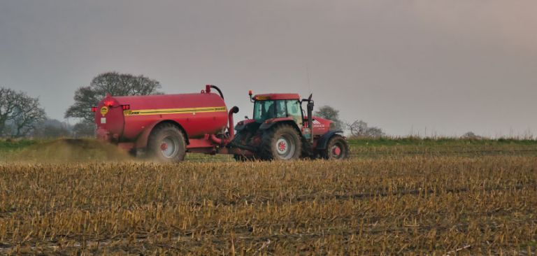 Tractor and muck spreader on farm