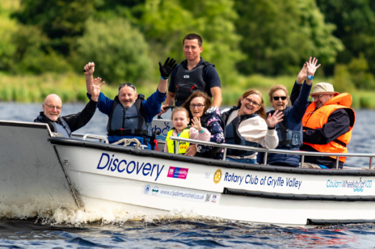 People in a boat on the water smiling and waving