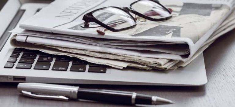 Newspapers sitting on top of laptop 