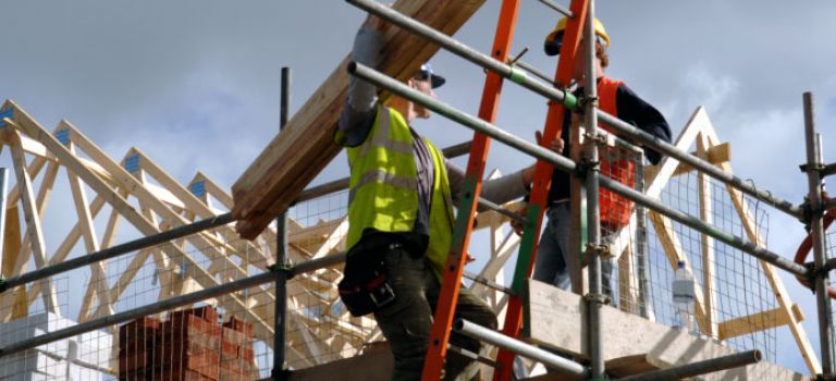 Two workers up scaffolding on construction site