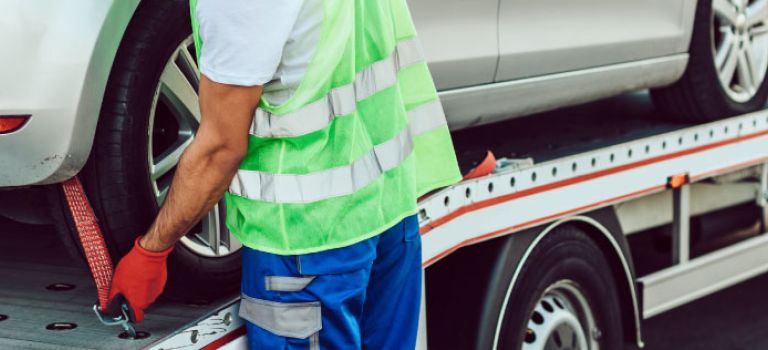 Man loading a car on to a car transporter truck