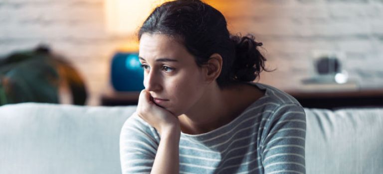 Woman sitting on sofa thinking