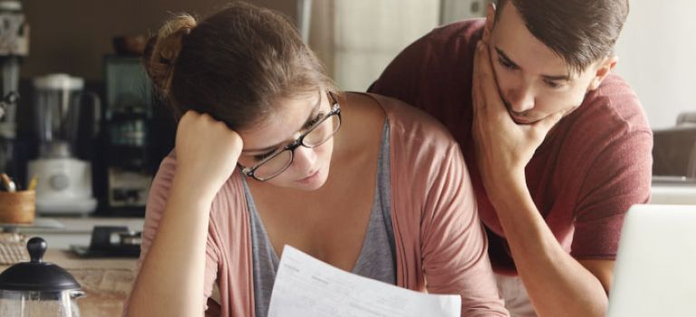 Young couple looking worried over bills