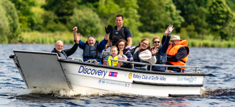 People in a boat on the water smiling and waving