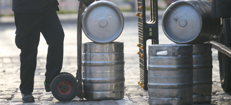 Delivery man bringing beer kegs out of a lorry on a trolley