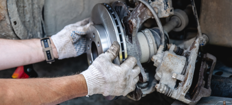 A car mechanic is fitting a brake in a car