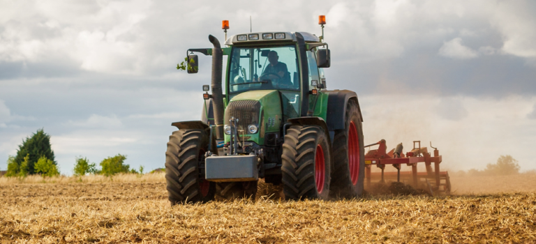 A green tractor is pictured on a farm