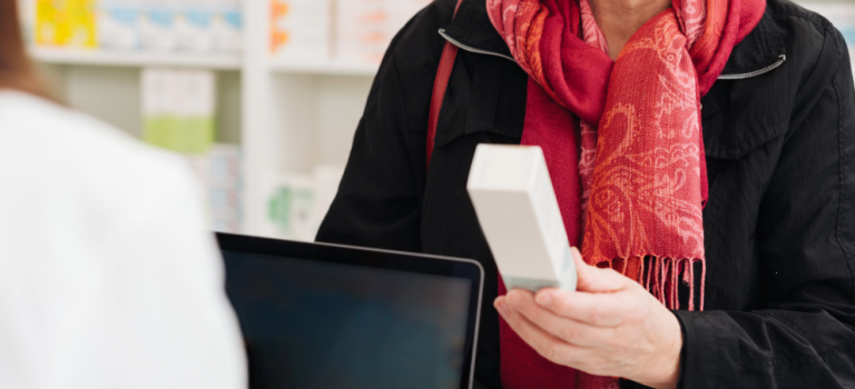 A woman is pictured holding medicine in a pharmacy