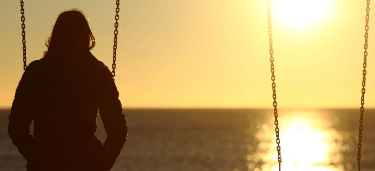 Woman sitting on swing watching sunset