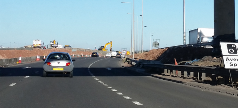 Car travelling along motorway with road works and average speed camera